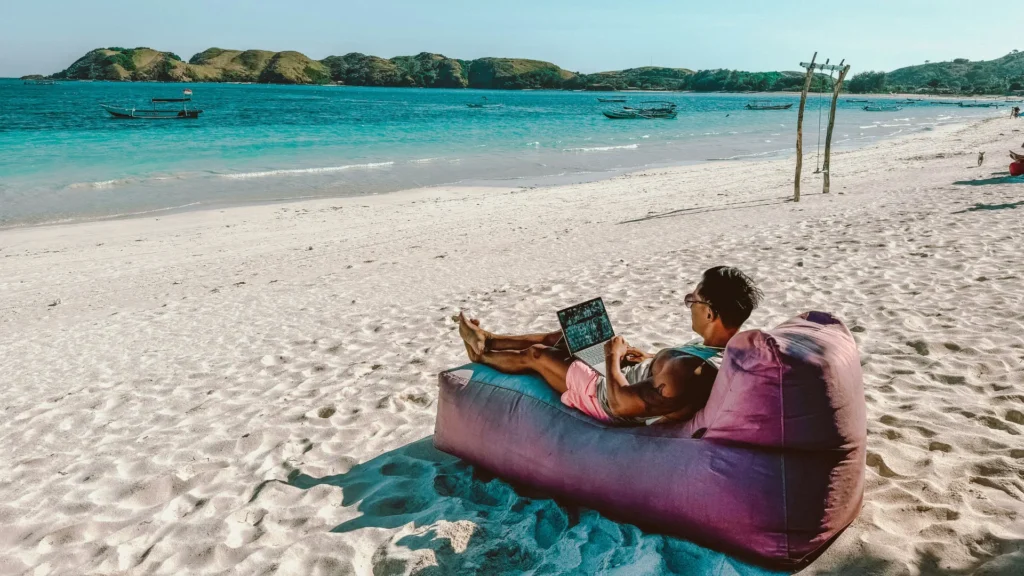 Een vakantieganger ontspant met een TopLaptop op het strand tijdens de vakantie